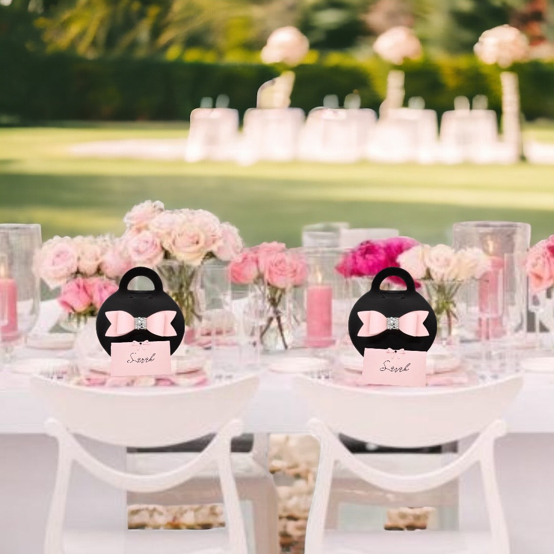 Elegant black purse favor bags with pink bows on a decorated outdoor party table