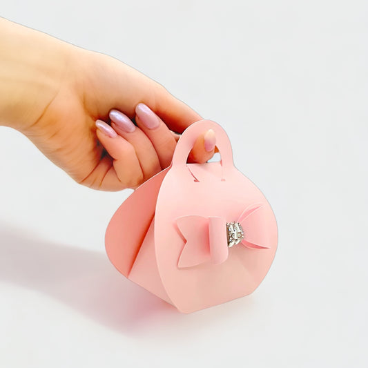 Dabble Doll blush purse favor bags with bow and rhinestone detail held by hand