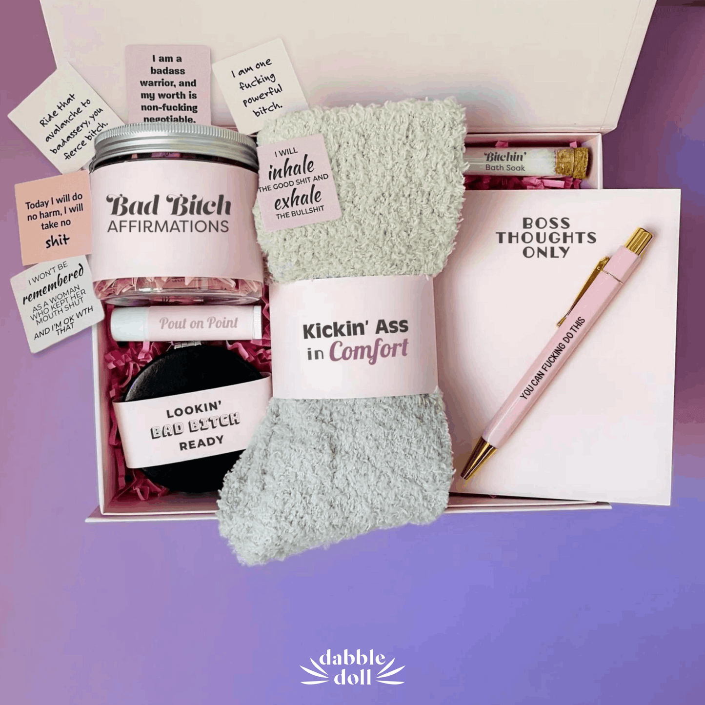Dabble Doll gift box featuring a badass bitch motivational jar affirmations, cozy socks, pen, notepad, and bath soak