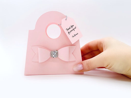 Dabble Doll blush mini purse favor bags with decorative bow and rhinestone held by hand