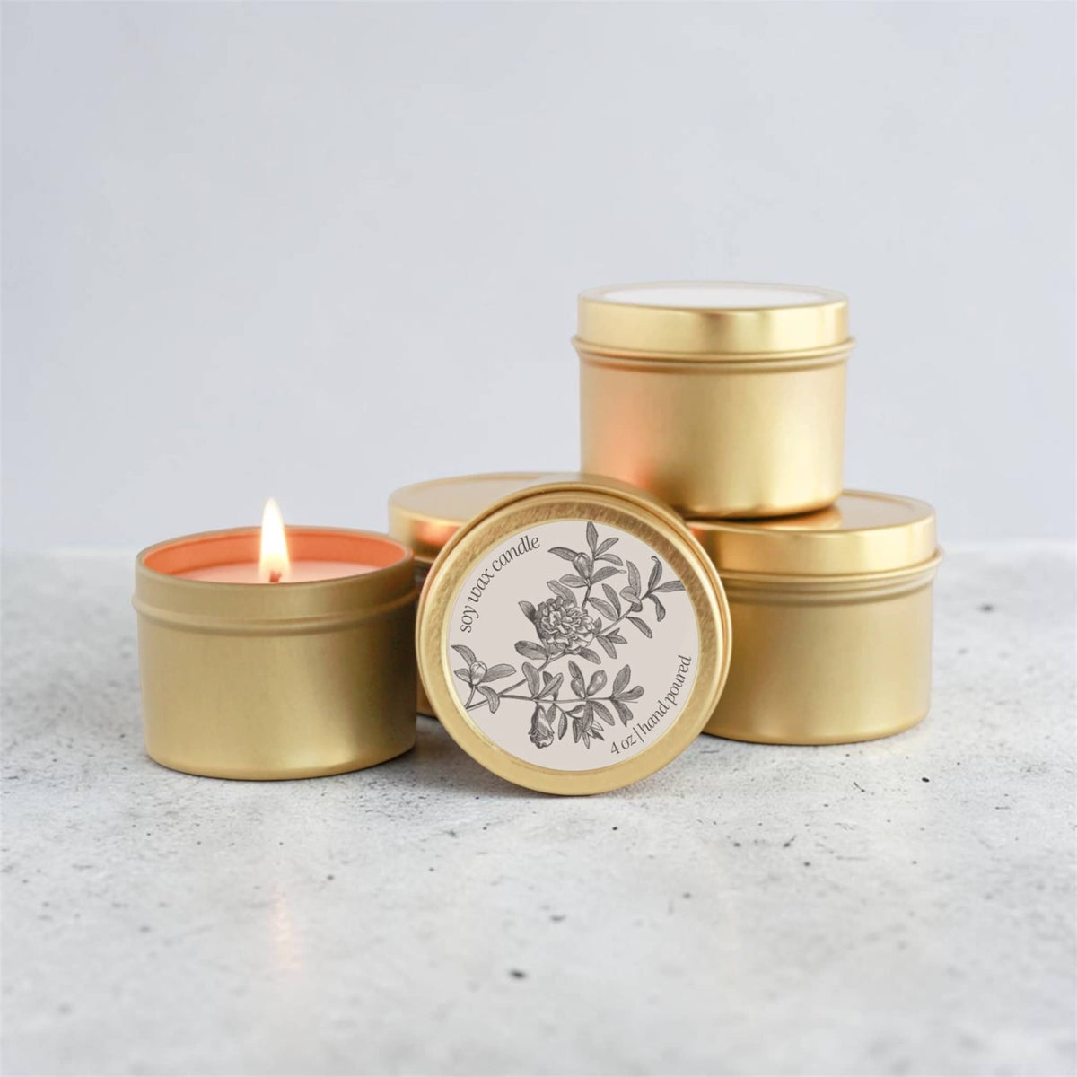 Dabble Doll Gift Box featuring gold tins of scented candle with floral design and a glowing candle