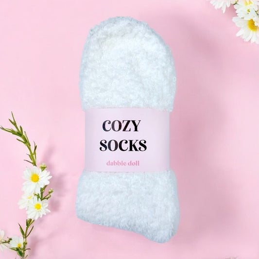 Dabble Doll white cozy socks for women wrapped with pink label on pink background with white flowers