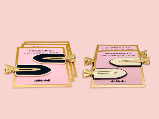 Dabble Doll creaseless hair clips in black and cream with gold edges on pink cards
