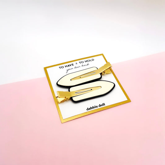 Dabble Doll creaseless hair clips in gold and ivory on branded card with pink and white background