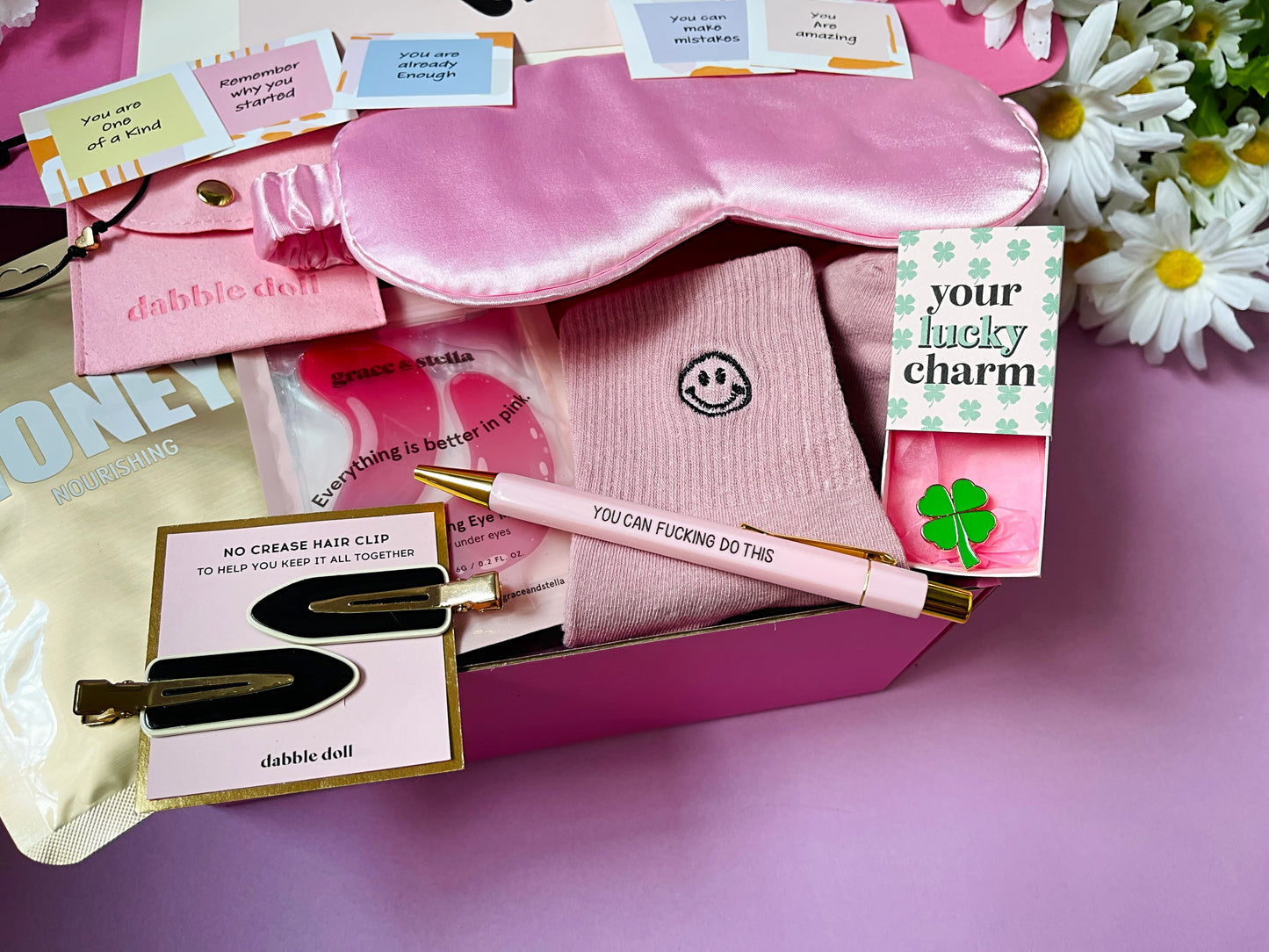 Dabble Doll good luck gift box with pink sleep mask, socks, lucky charm, hair clips, and motivational cards