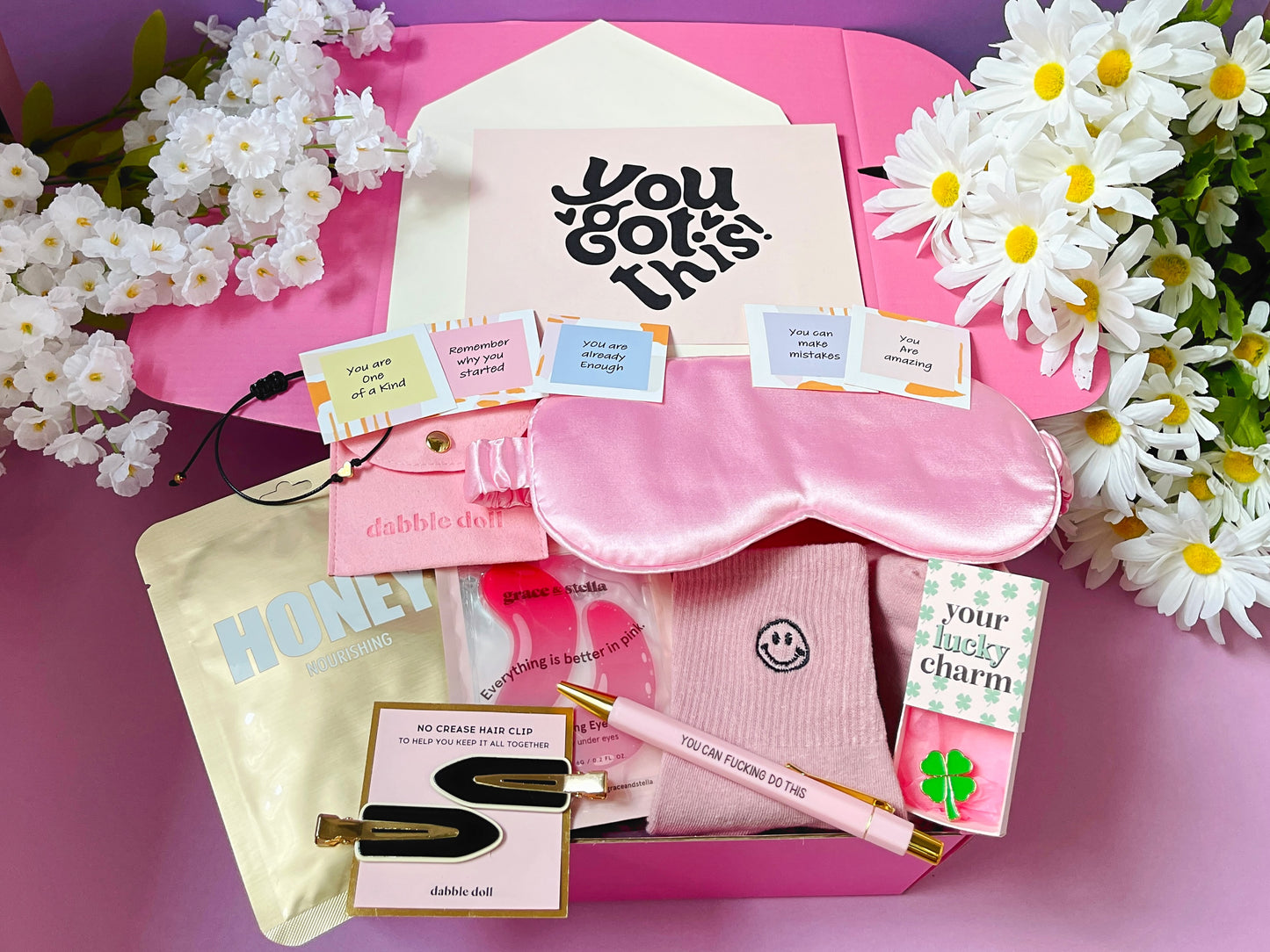Dabble Doll good luck gift box with pink sleep mask, motivational cards, pen, honey mask, and lucky charm package