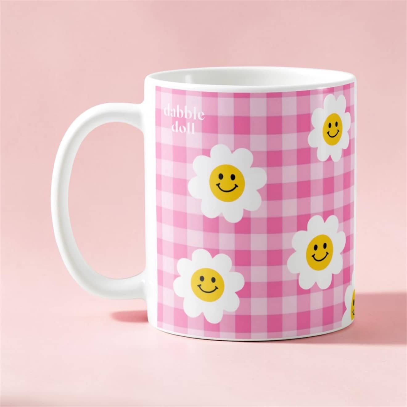 Dabble Doll smiley face mug with a pink checkered design and cheerful flower graphics