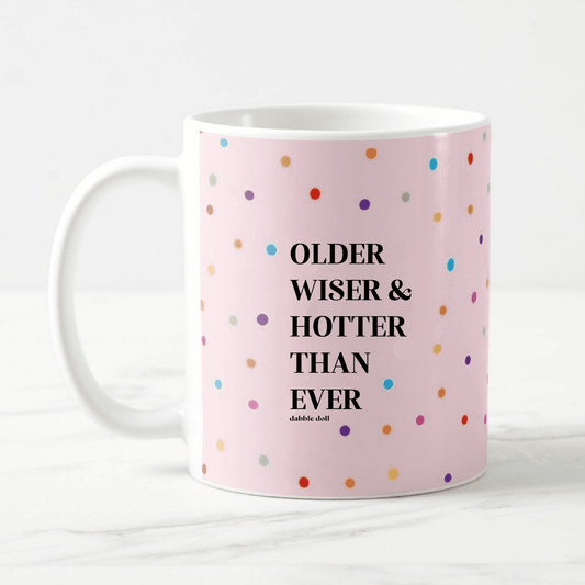 Funny coffee mug by Dabble Doll with colorful polka dots and the phrase Older Wiser & Hotter Than Ever