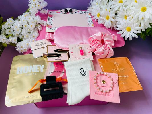 Pink gift in box by Dabble Doll with goodies for girls, including hair accessories and skincare items