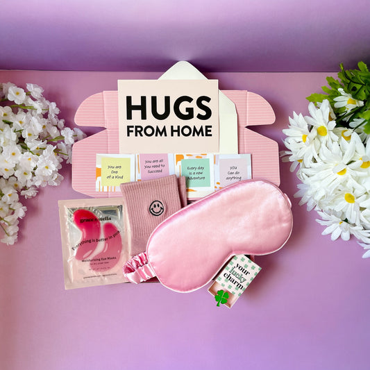 Dabble Doll hugs gift box with pink eye mask, motivational cards, socks, and moisturizing eye mask