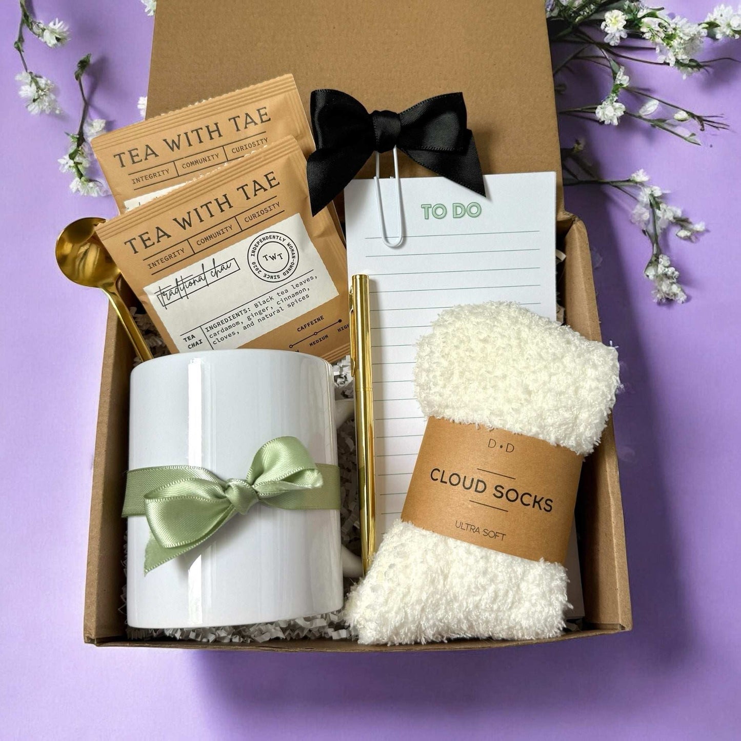 Cozy self care gift box with tea packets mug with green bow fluffy socks and to do list