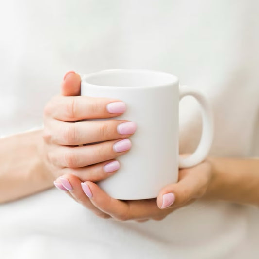 Hands holding a white mug representing a cozy self care gift box by Dabble Doll