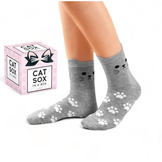 Cute gray cat socks with paw prints and cat face design by Dabble Doll shown on feet with packaging box