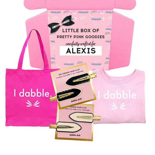 Personalized custom gift box from Dabble Doll filled with hand-picked goodies, next to a pre-made curated gift box