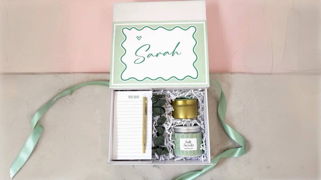 Personalized gift box for women featuring a green and gold spa scrub, notepad, and pen