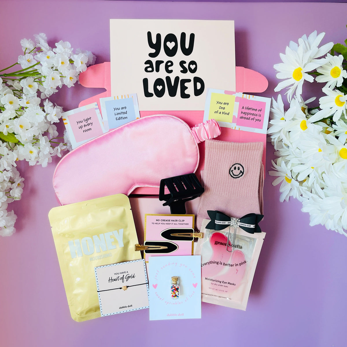 Self care gift box with pink eye mask, cozy socks, and honey jar from Dabble Doll