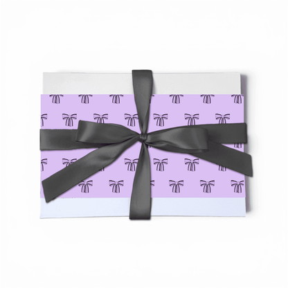 Gift box with purple pattern and black ribbon on a white background