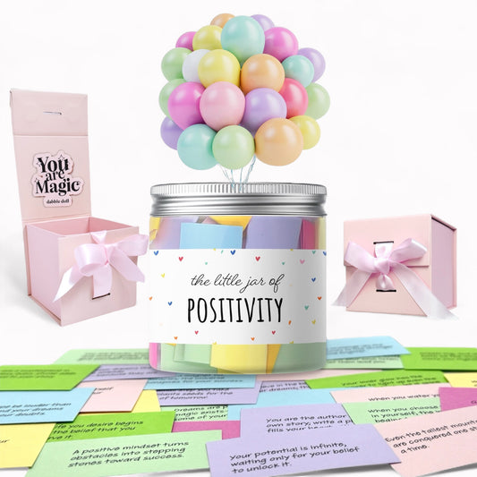 Jar labeled 'the little jar of Positivity' with pastel balloons and gift boxes on a white background