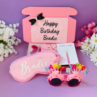 Pink gift box for women featuring a birthday sleep mask, funny glasses, and celebration card