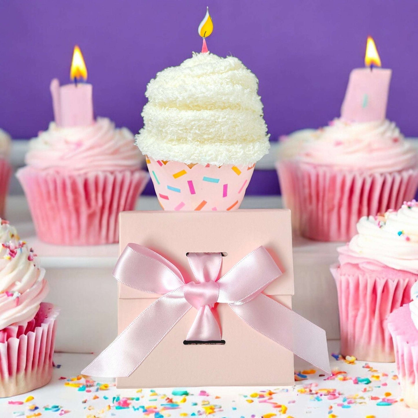 Dabble Doll birthday gift box adorned with a pink ribbon, surrounded by colorful cupcakes