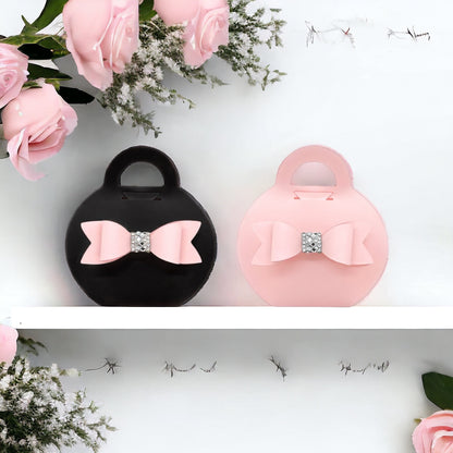 Dabble Doll black purse favor bags with pink bow and rhinestone detail displayed with pink roses