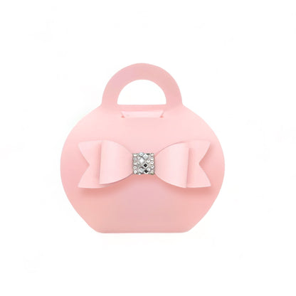 Blush purse favor bags with a bow and rhinestone detail for elegant party favors
