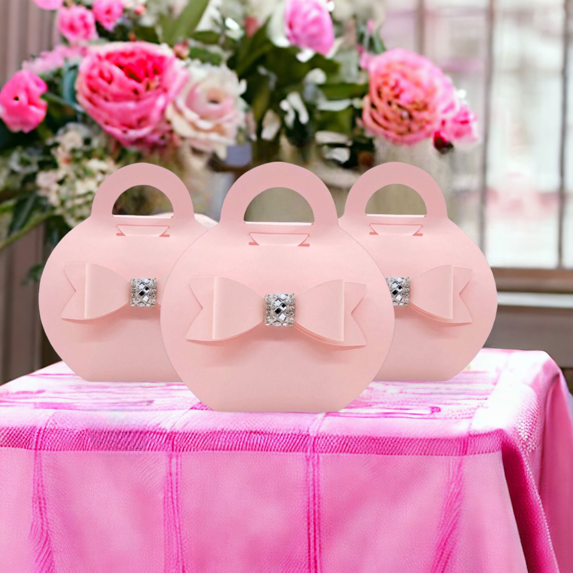 Dabble Doll blush purse favor bags with decorative bows and rhinestone centers on pink tablecloth