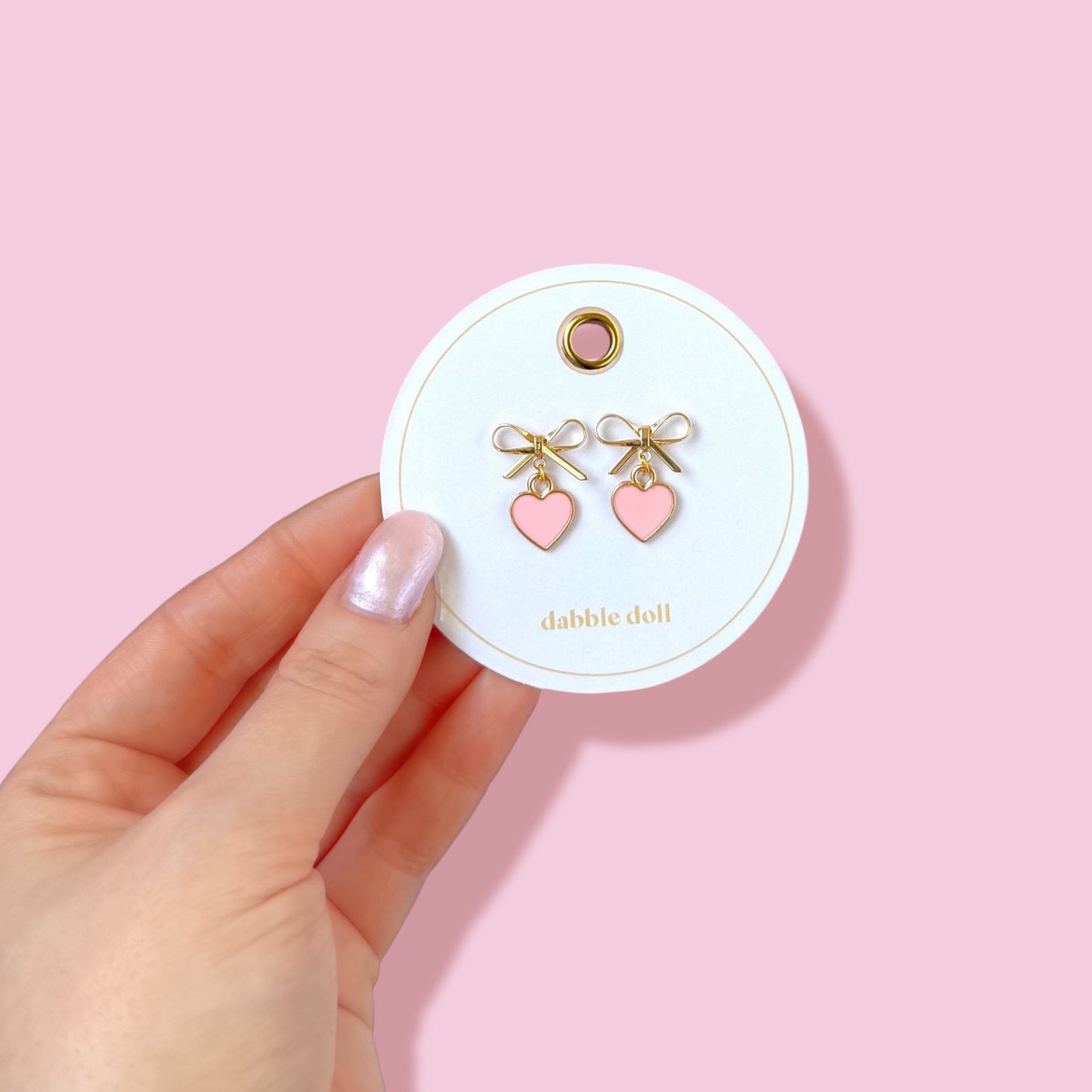 Dabble Doll Pink Bow Earrings with Heart Accents on Display Card