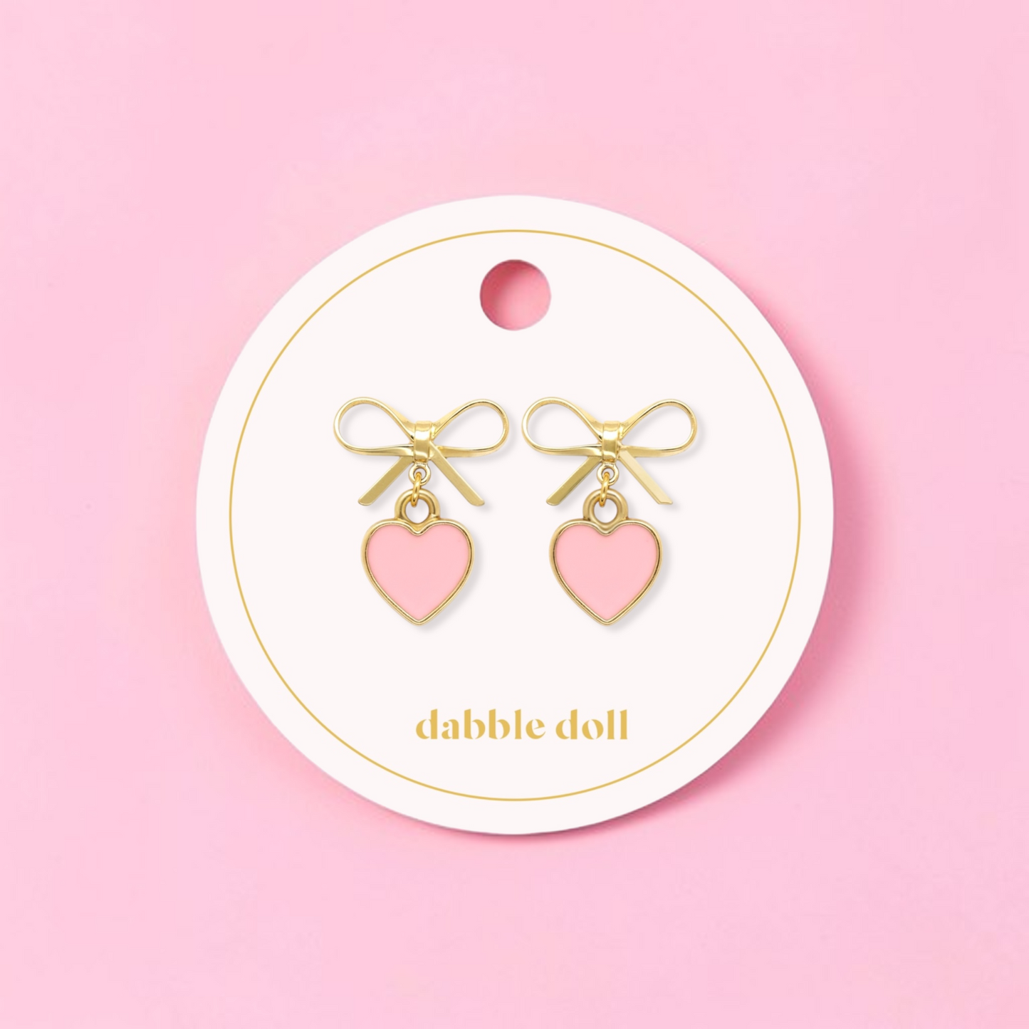 Dabble Doll bow earrings featuring gold accents and pink heart charms for a cute accessory look