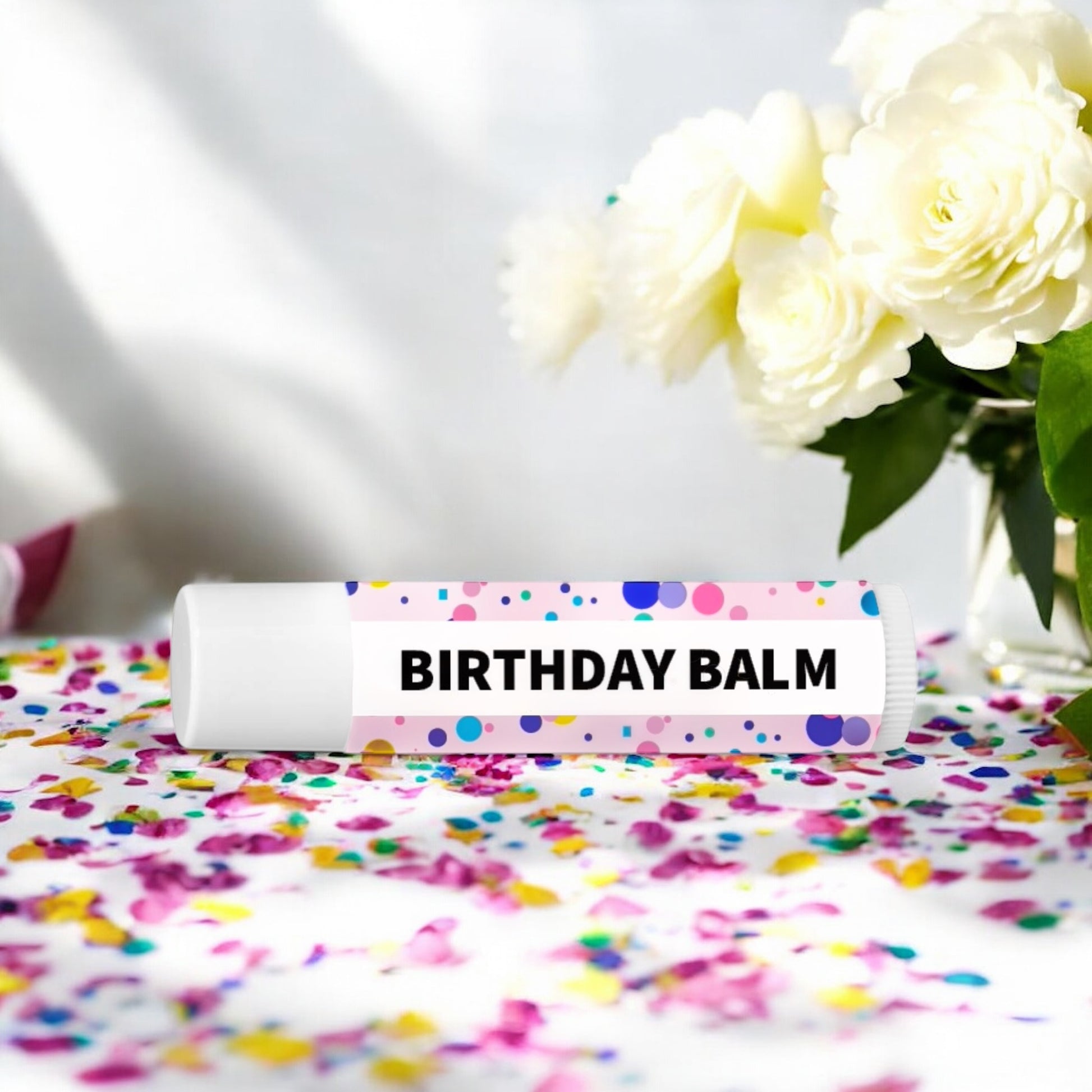 Dabble Doll Birthday Balm tube on a colorful confetti background for chapped lip balm