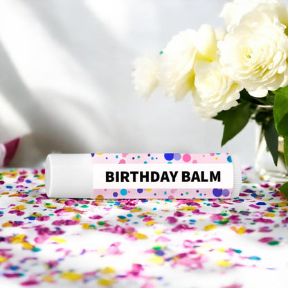 Dabble Doll Birthday Balm tube on a colorful confetti background for chapped lip balm