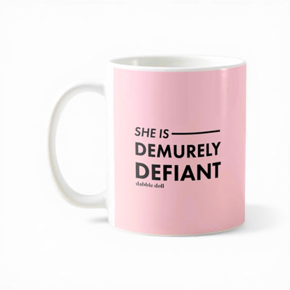 Dabble Doll pink coffee mug featuring the phrase She Is Demurely Defiant for a bold gift idea