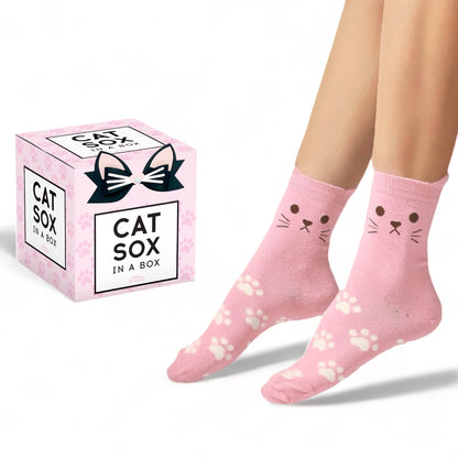 Cute pink cat socks with cat face and paw prints worn on feet beside Cat Sox in a Box packaging