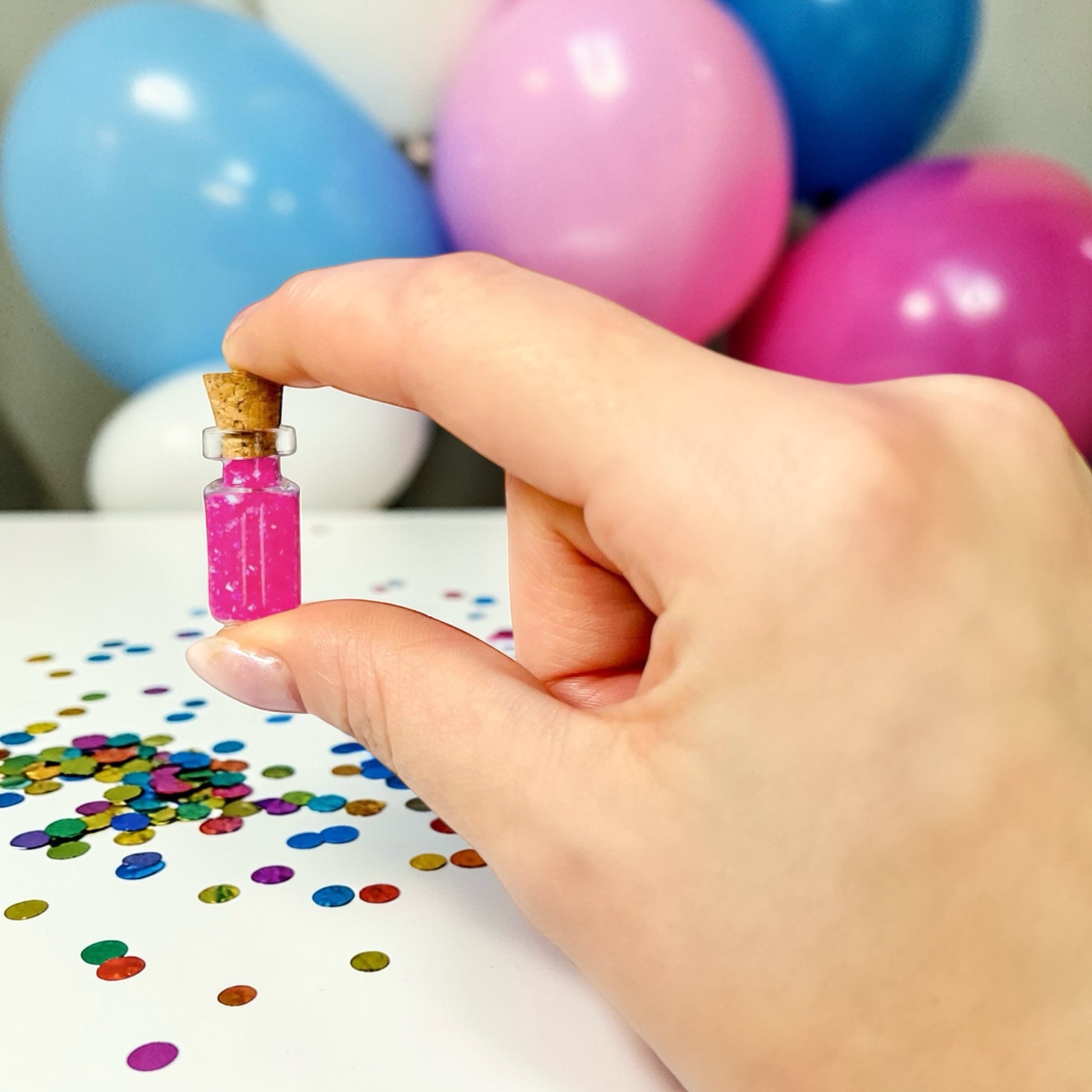 Dabble Doll birthday gift box with a miniature colorful jar held above festive confetti and balloons