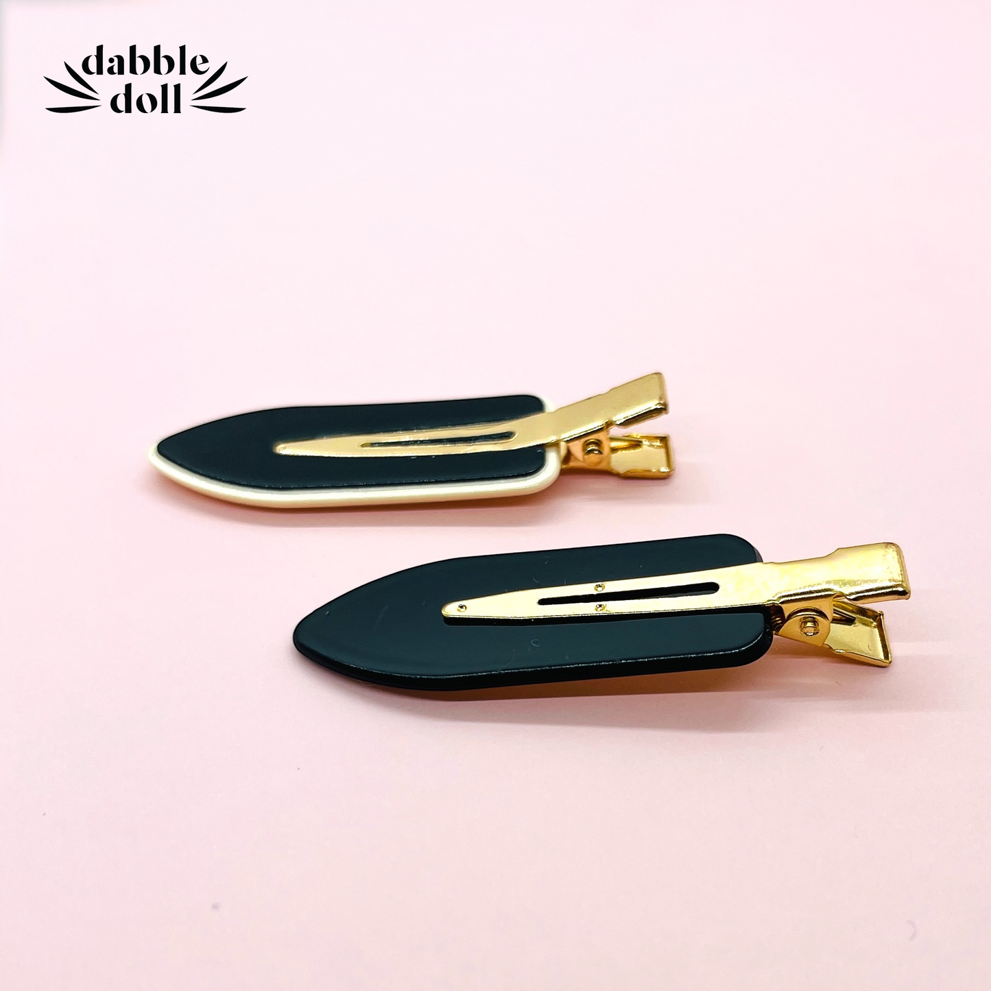 Dabble Doll black no bend hair clips with gold metal details on a pink background