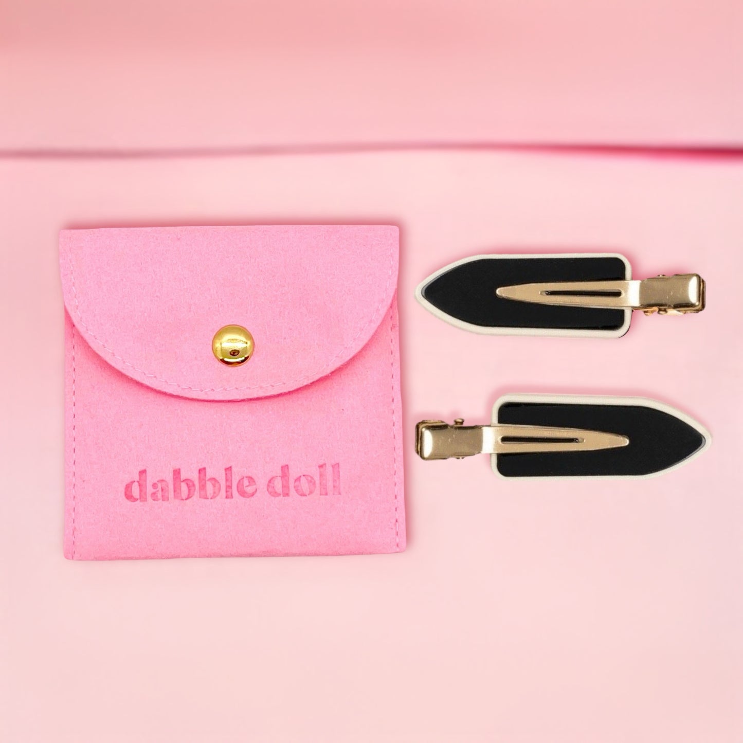 Dabble Doll black no bend hair clips with gold accents and pink storage pouch on light pink background