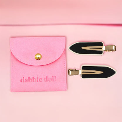 Dabble Doll black no bend hair clips with gold accents and pink storage pouch on light pink background