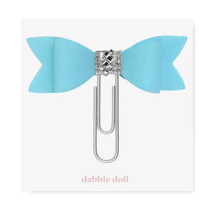 Dabble Doll Bow paperclip in blue with a decorative jewel center for stylish organization