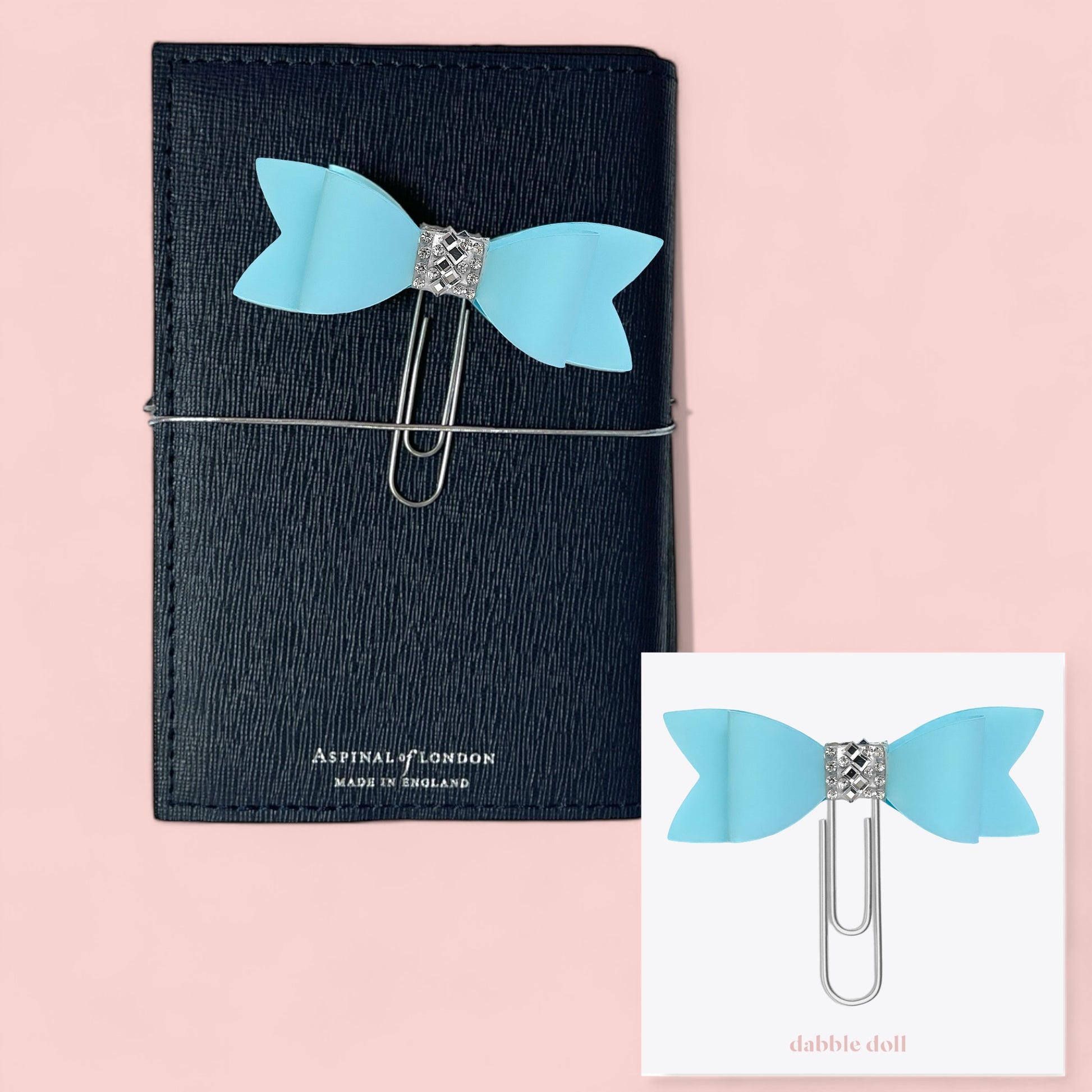 Dabble Doll Bow paperclip in blue attached to a black notebook for stylish organization