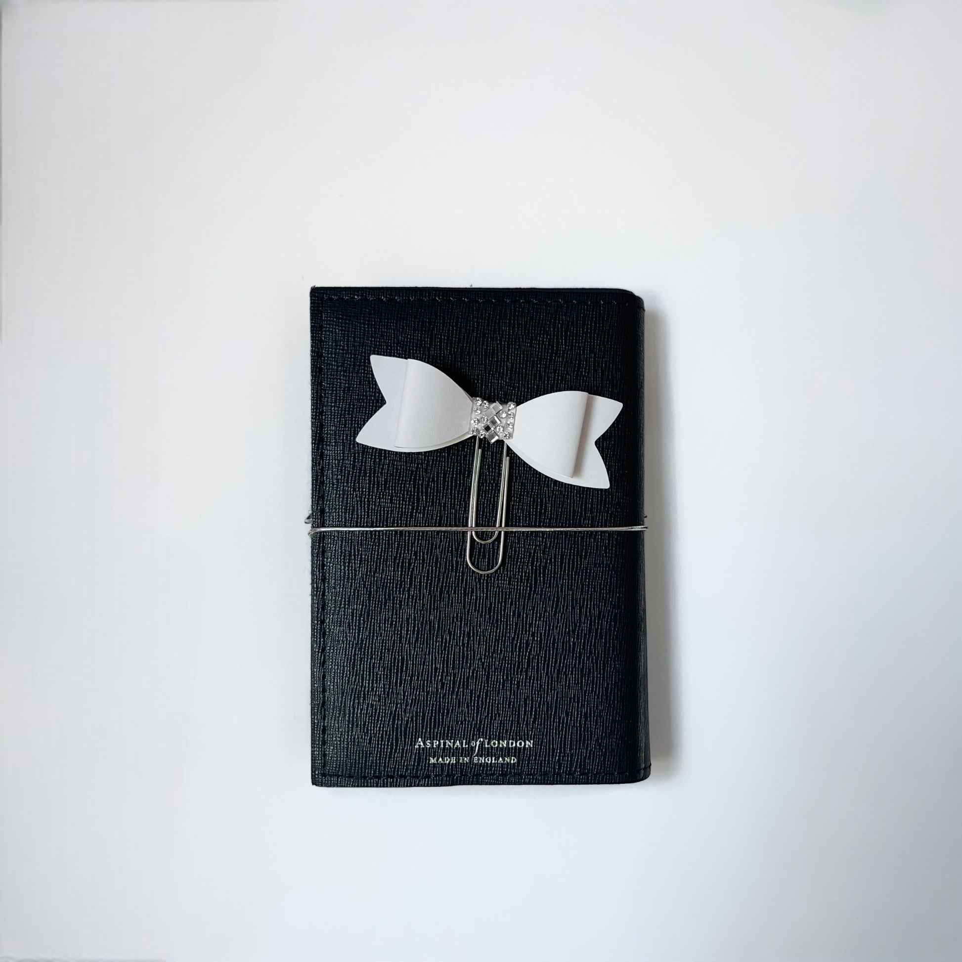 Dabble Doll Bow paperclip on a black notebook, perfect for holding pages together with style
