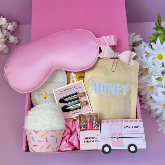 Dabble Doll pink gift box with gift featuring sleep mask, cosmetics, and party accessories