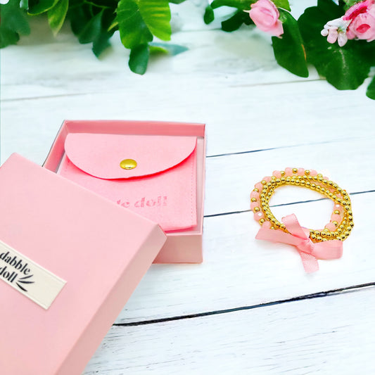 Dabble Doll pink bracelet stack with beads and ribbon, perfect for girls and women.