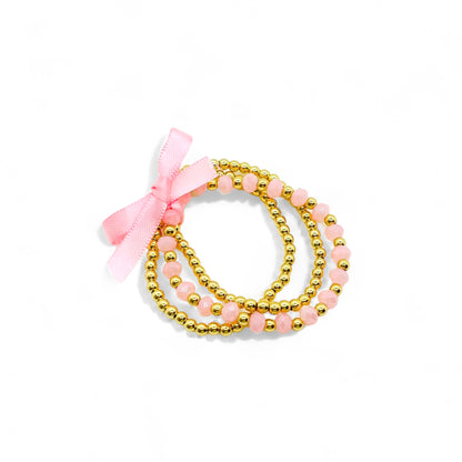 Gold and pink bracelet stack for girls with beads and a cute bow for stylish women