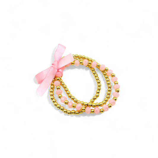 Gold and pink bracelet stack for girls with beads and a cute bow for stylish women
