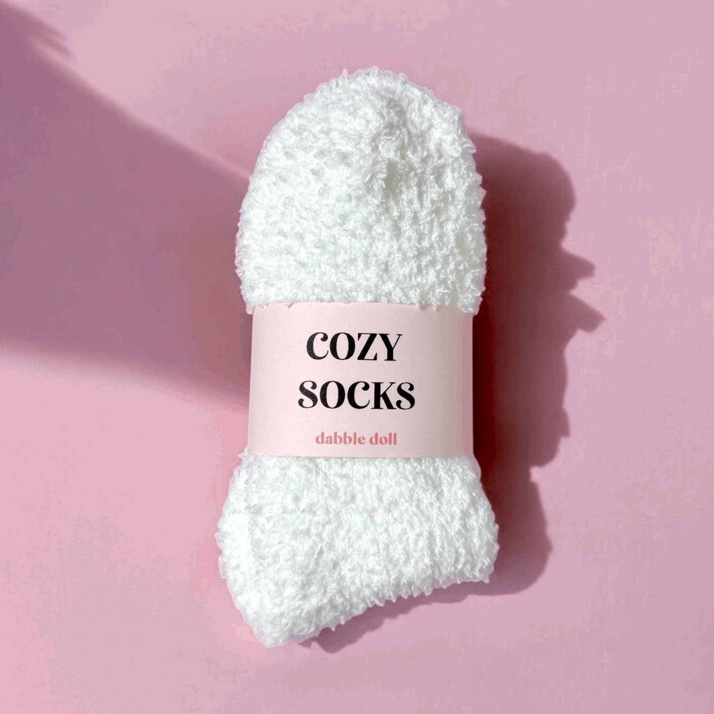 Dabble Doll cozy socks for women in white fluffy fabric against pink background