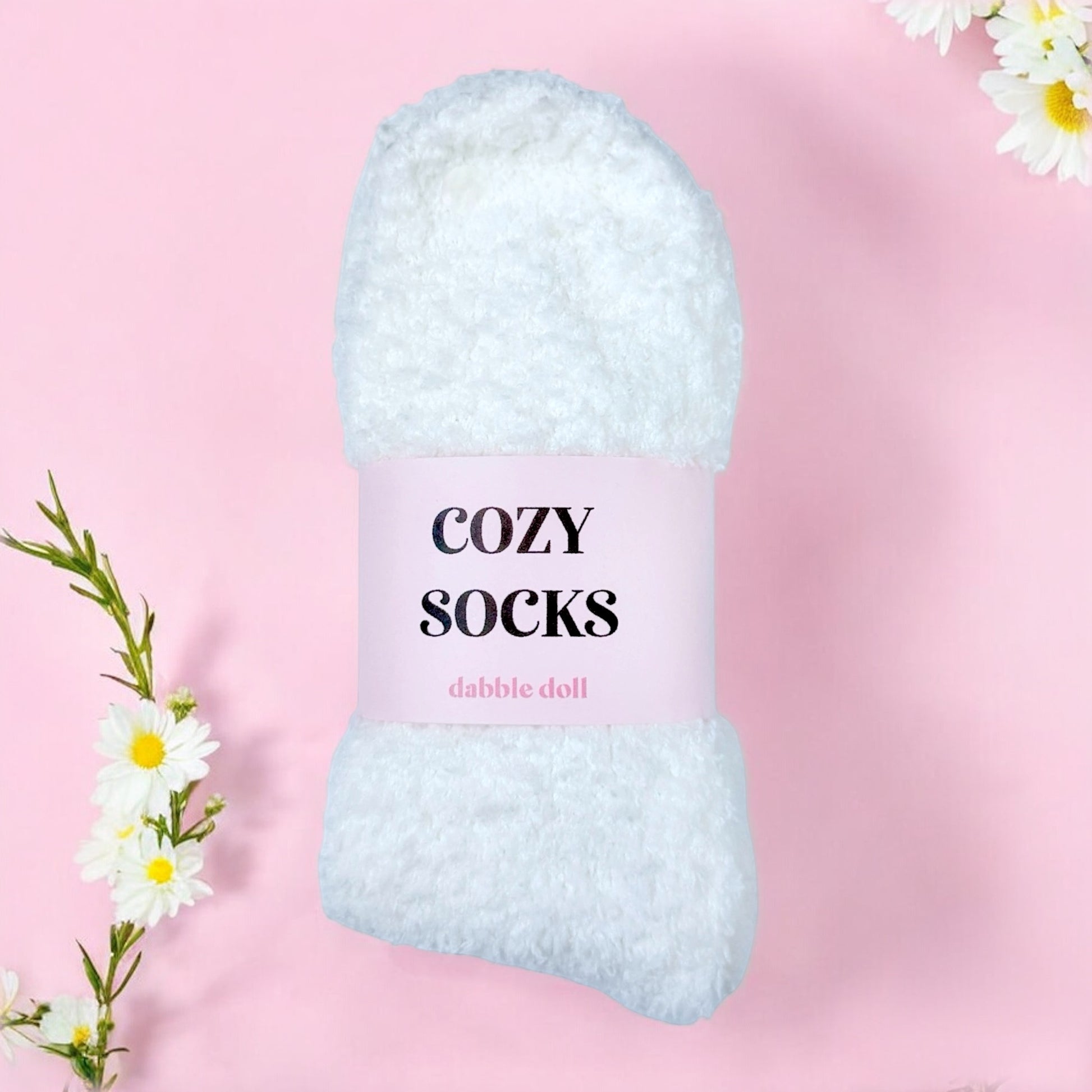 Dabble Doll white cozy socks for women wrapped with pink label on pink background with white flowers