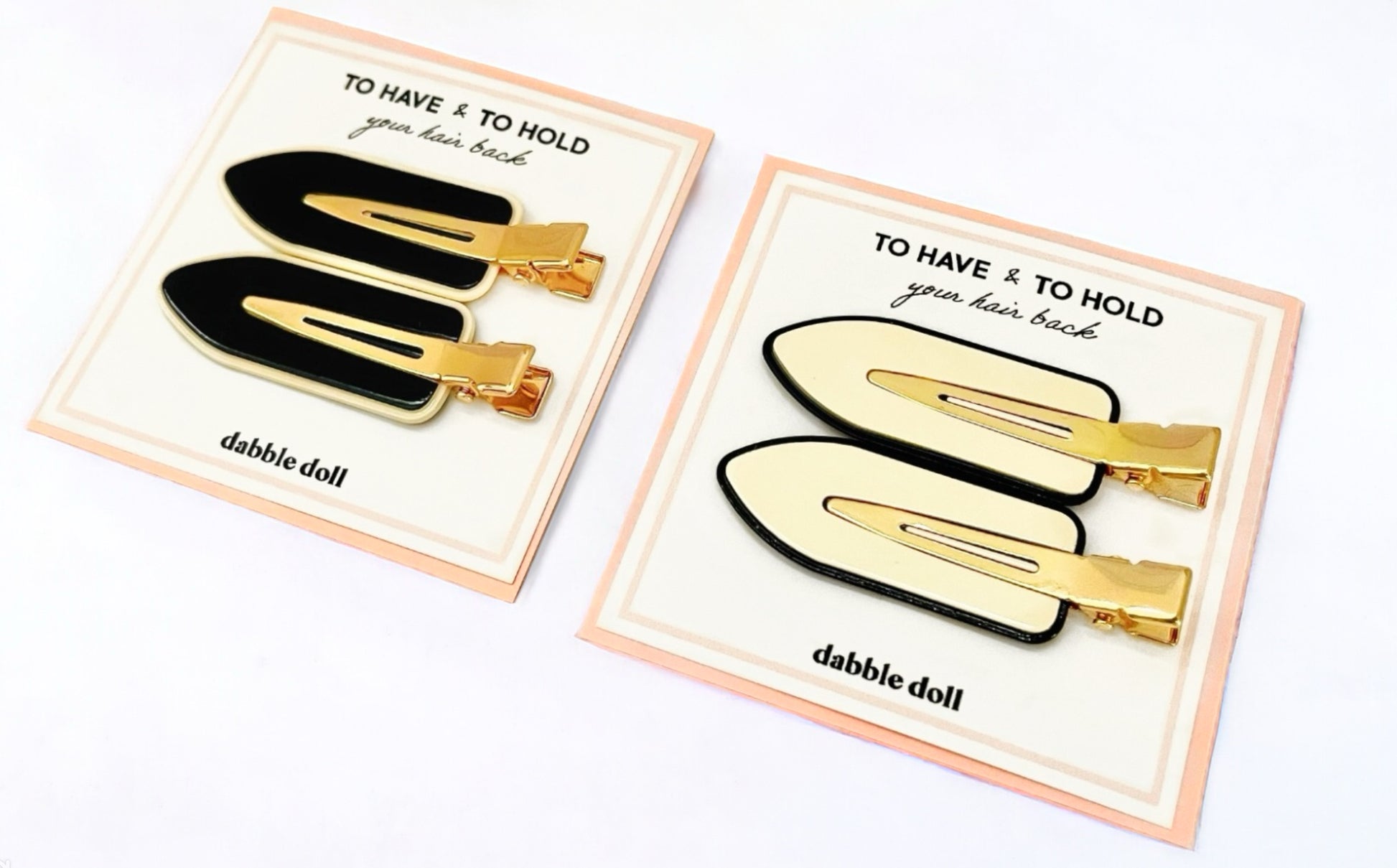 Dabble Doll crease free hair clips in black and white with gold accents on display cards