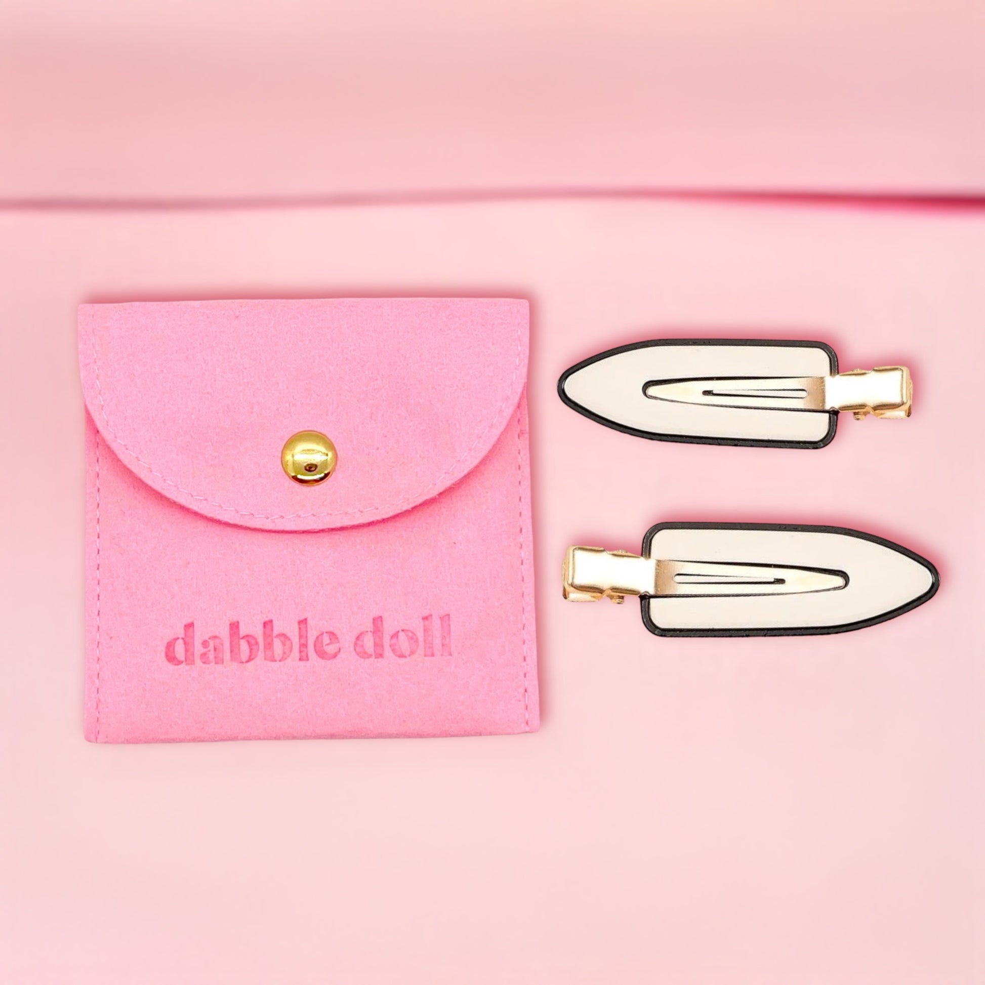 Dabble Doll creaseless clips for styling with black and white finish alongside pink carrying pouch