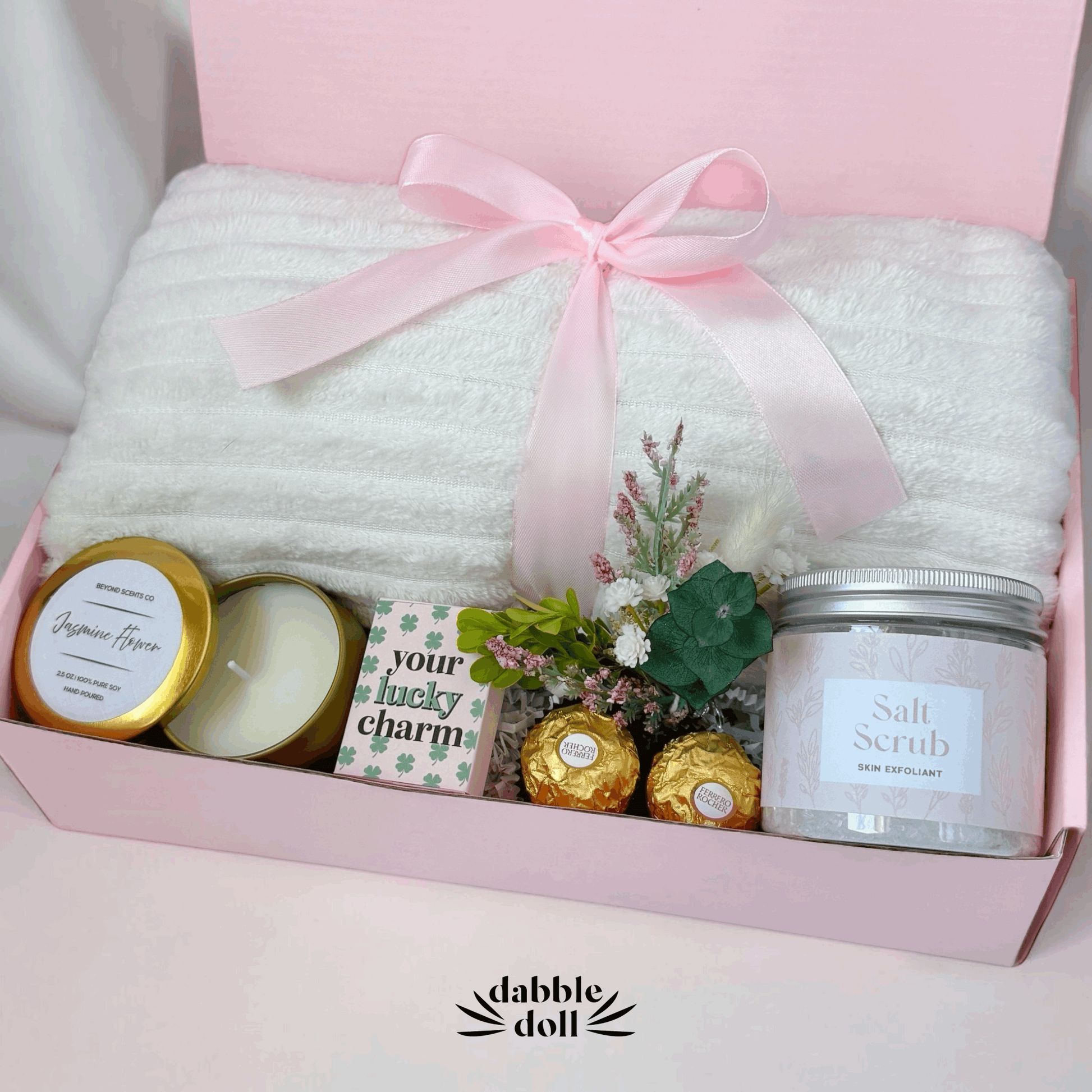 Dabble Doll gift box for women featuring a soft white blanket, candles, and beauty products in pink packaging