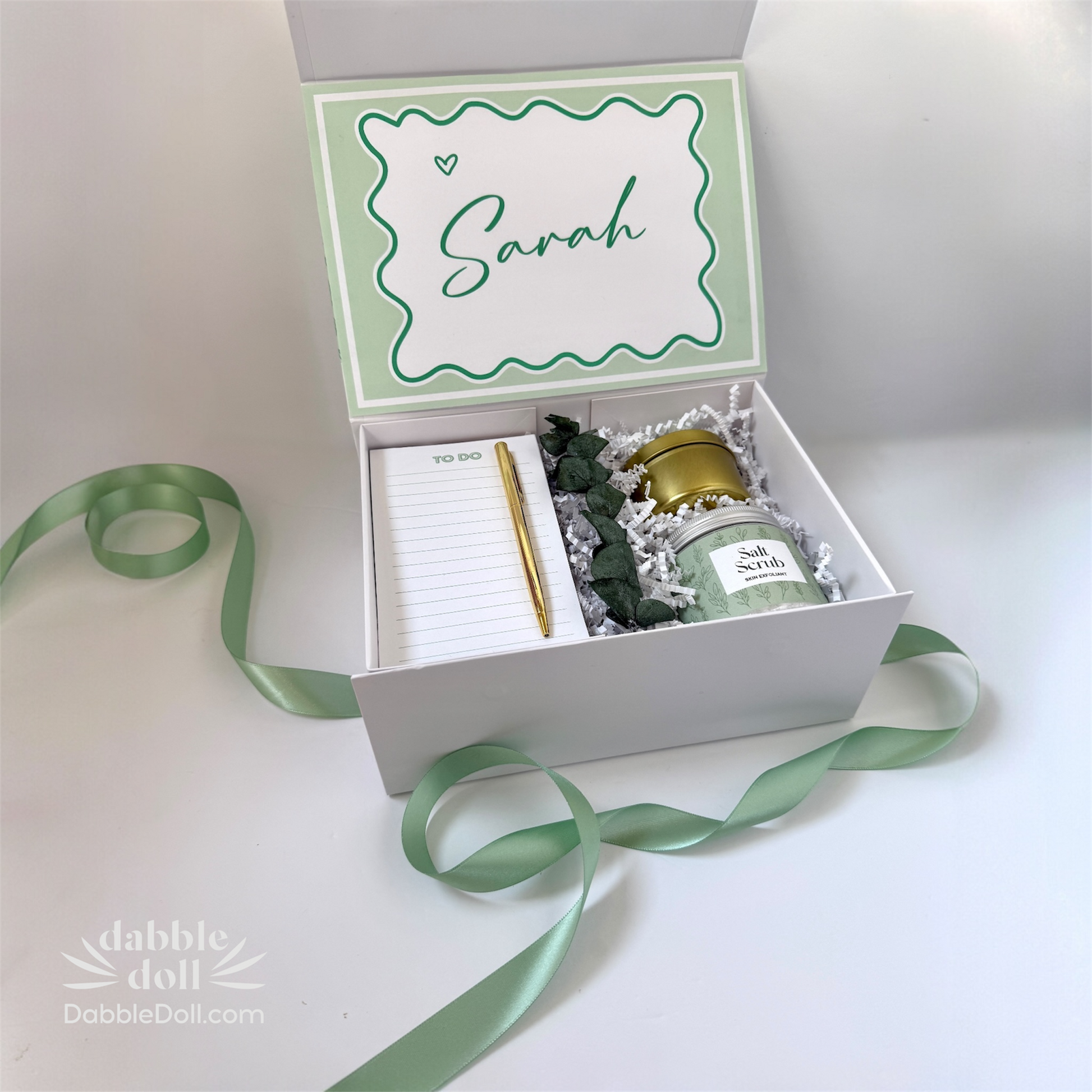Dabble Doll personalized gift box with a note pad, scented candle, and green ribbon